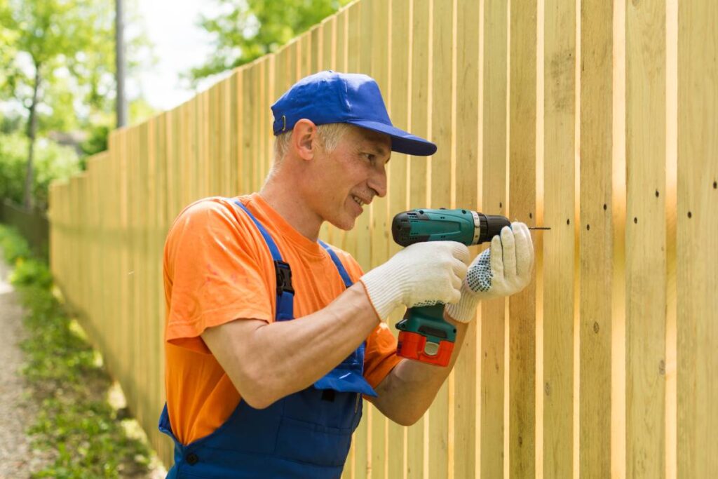 A professional fencing contractor installs a wooden fence near a home in Nicholasville, KY