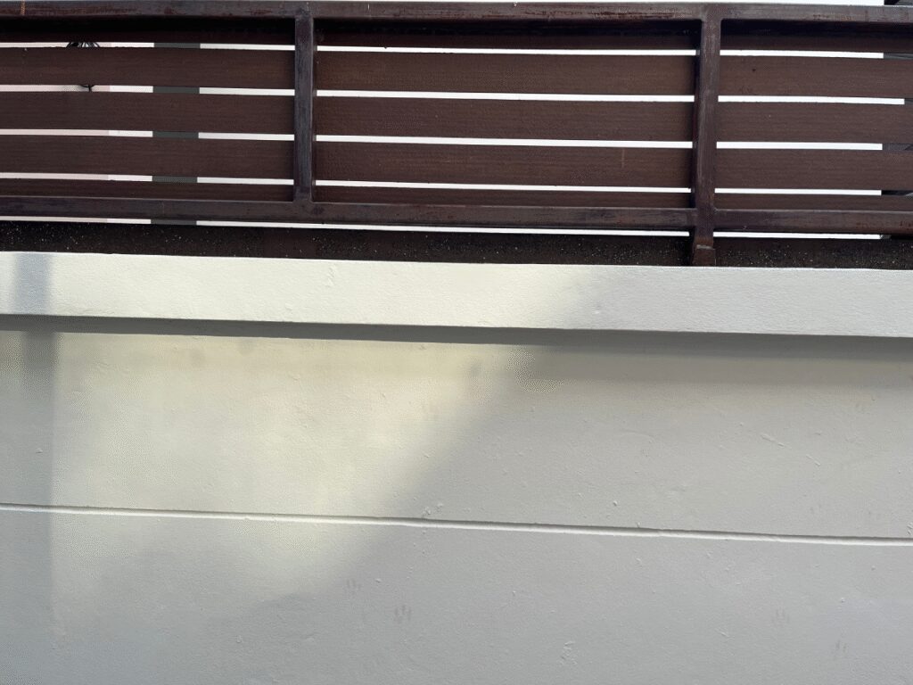 Wooden fence topper on a concrete wall.