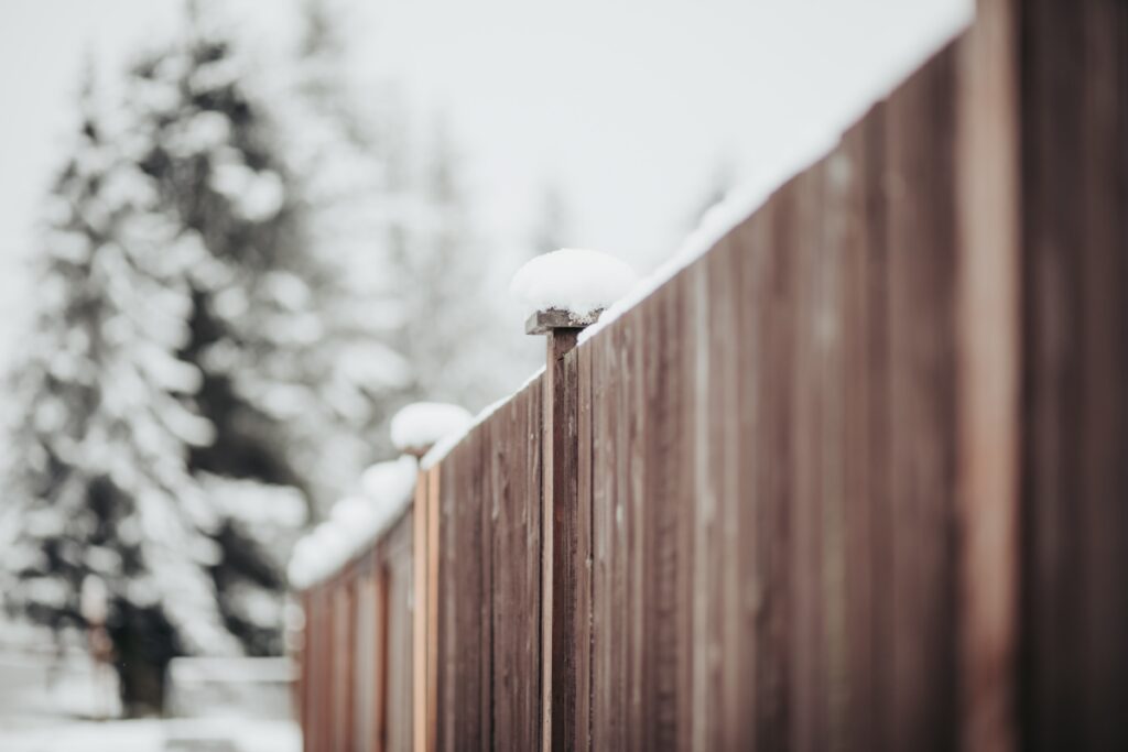 Wood fence topped with snow during winter.